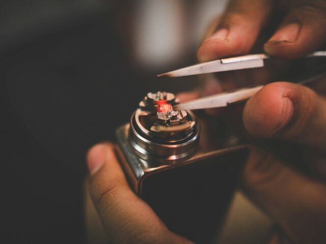 Hands trimming wick on a rebuildable deck