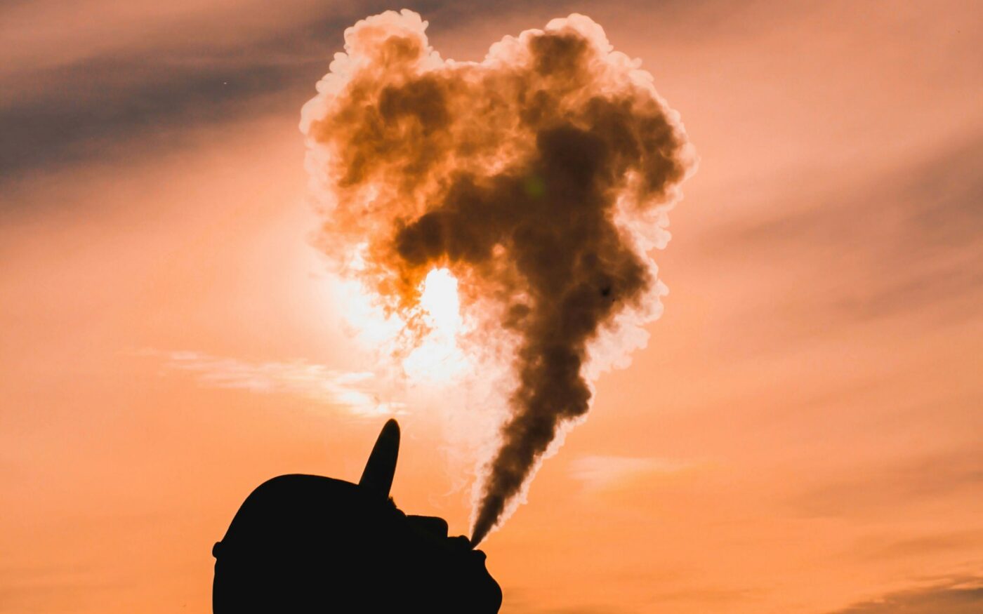 Silhouette exhaling vapour against a sunset