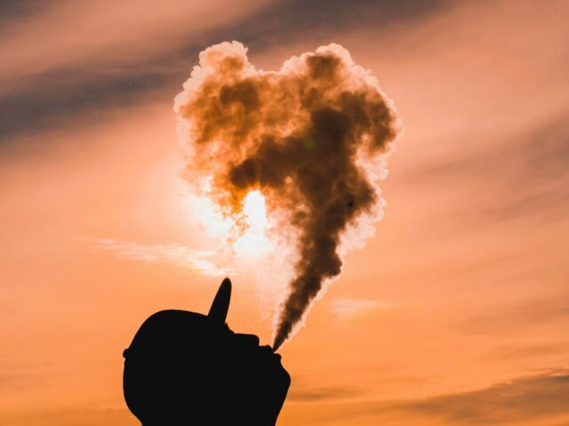Silhouette exhaling vapour against a sunset