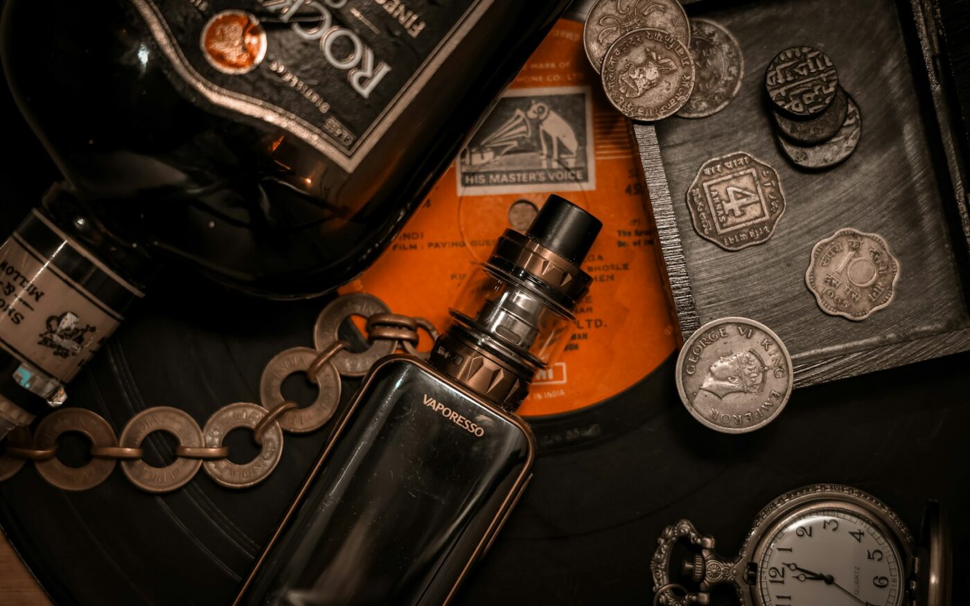 Box mod and tank among coins and vintage objects