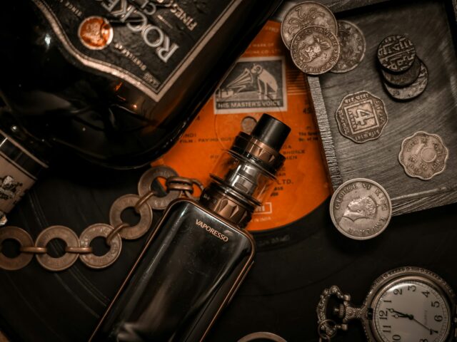 Box mod and tank among coins and vintage objects