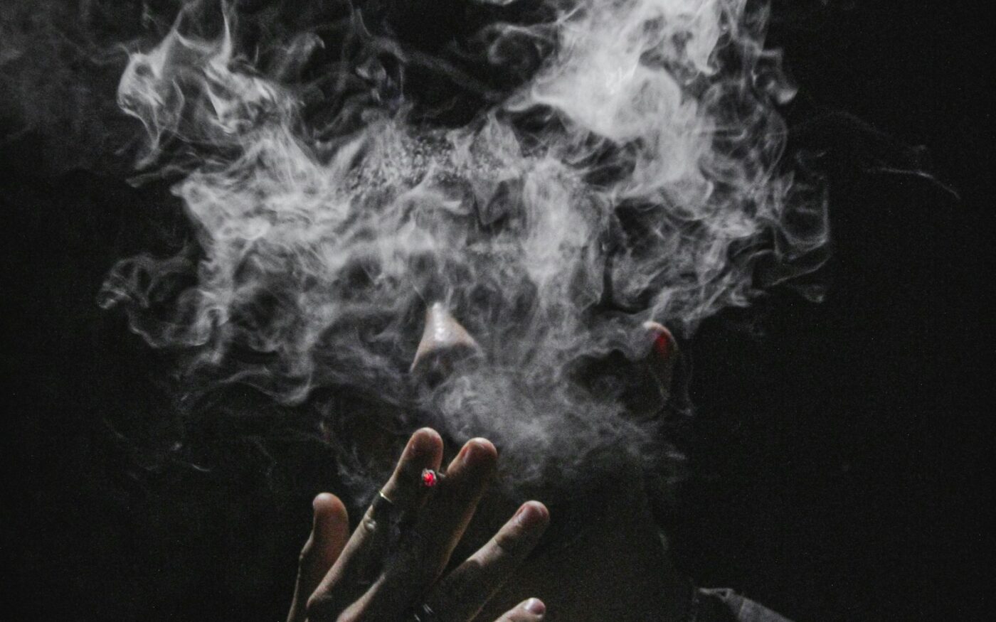 Person exhaling a thin stream of vapour