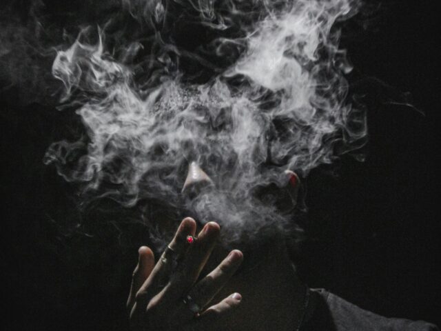 Person exhaling a thin stream of vapour